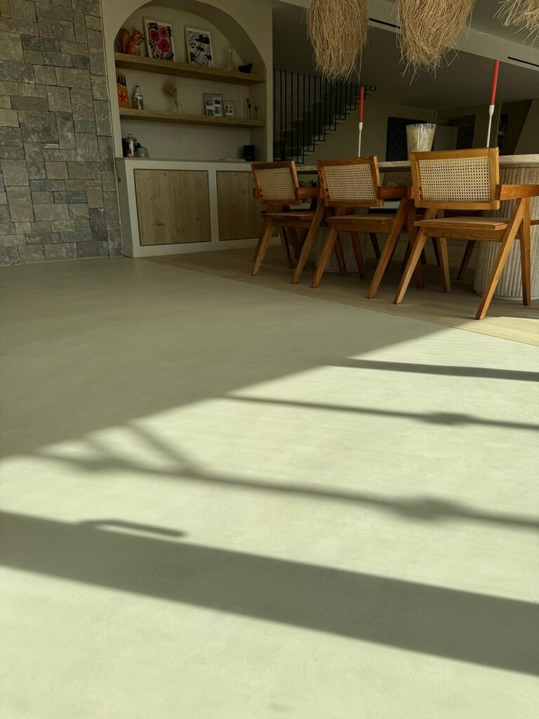 Salle à manger moderne, chaises bois, mur pierre, lumière naturelle, style élégant et intemporel.