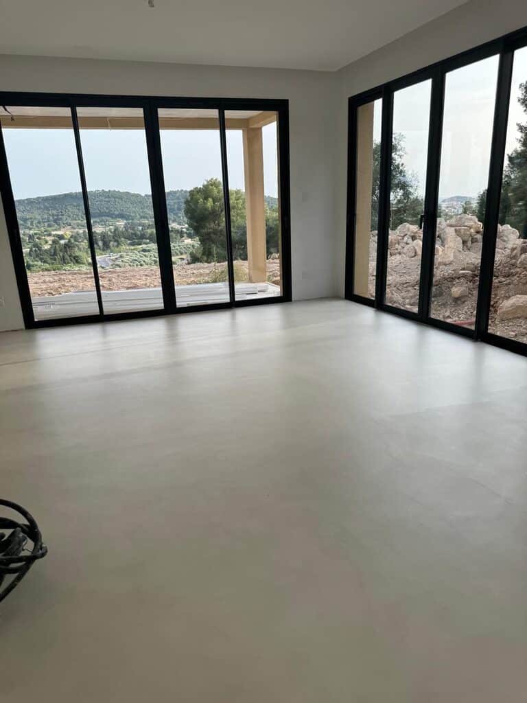 Espace lumineux, sol clair, grandes baies vitrées sur paysage rocheux, murs blancs élégants.