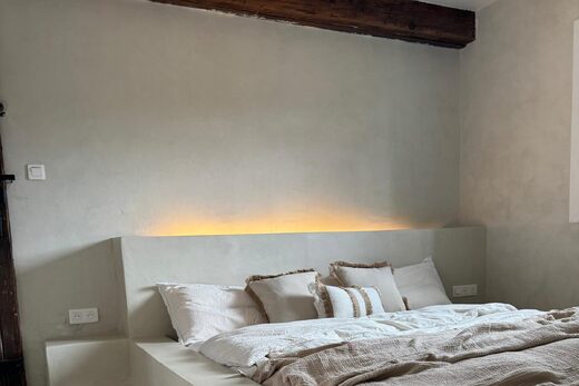 Chambre épurée avec lit plateforme, lumière douce et sols raffinés dans l'esprit béton ciré.