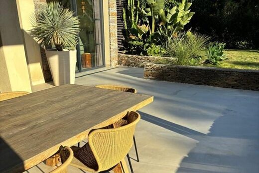 Terrasse élégante, mobilier en bois, végétation luxuriante, lumière naturelle sublimant chaque détail.