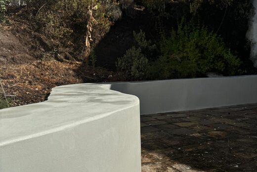 Mur béton arrondi sublime patio dallé, entouré de verdure pour une ambiance élégante et intemporelle.