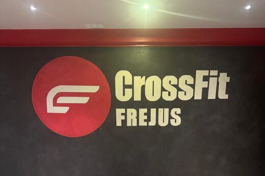 Mur noir chic, logo rouge, lettrage CrossFit FREJUS, sol béton brut élégant et contemporain.